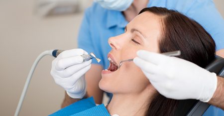 21246825 – mature dentist examining female patients mouth in clinic